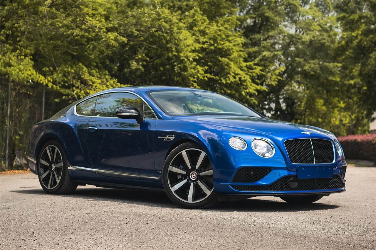 Blue Bentley Continental GT parked by trees